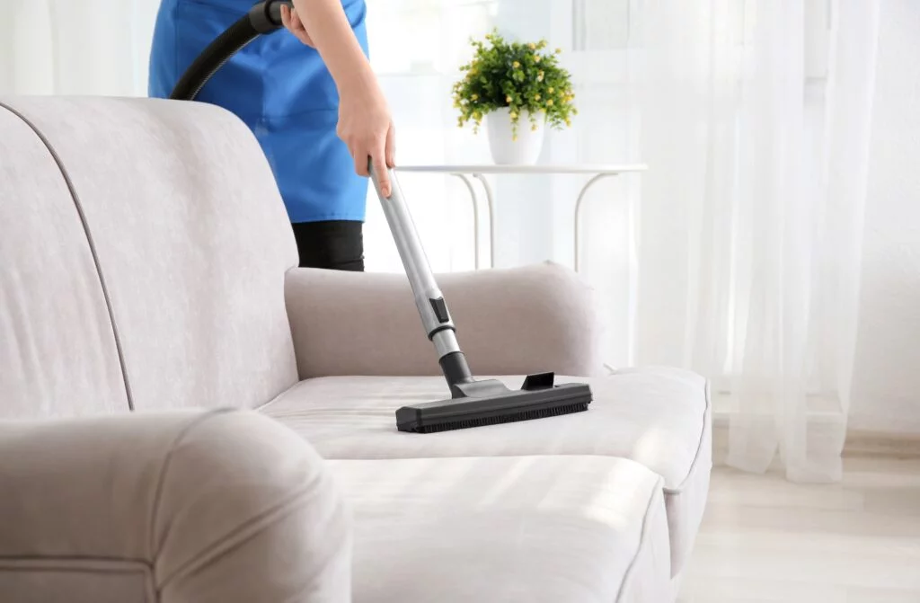 Woman hoovering sofa cushion, Martina's Cleaning, cleaner in Melksham and Devizes