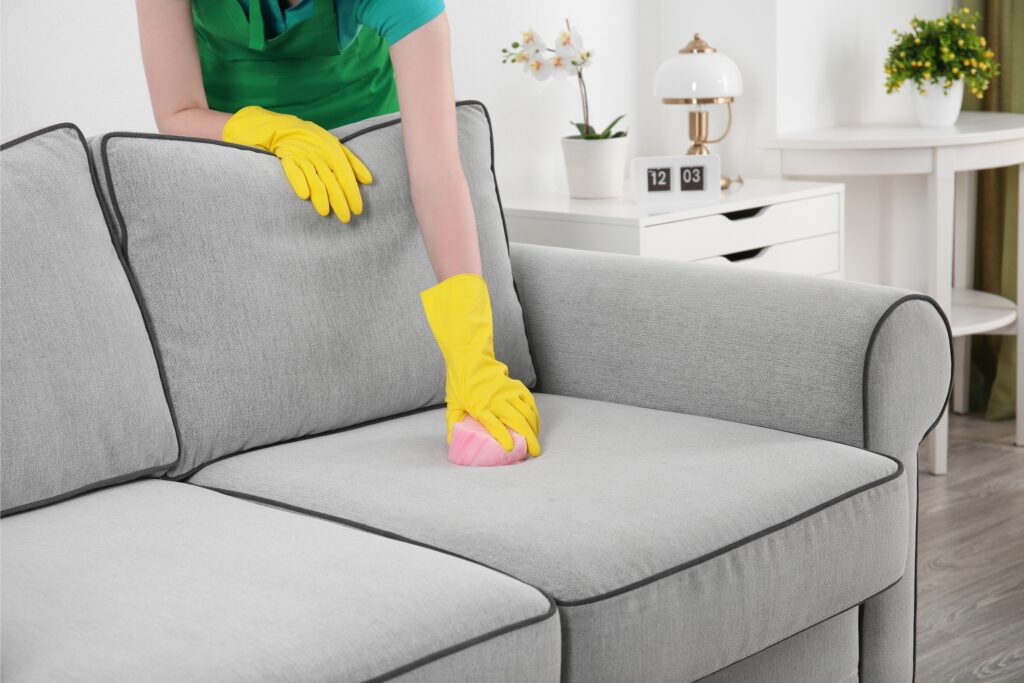 Woman wiping down sofa cushion with pink cloth, Martina's Cleaning, cleaner in Melksham and Devizes